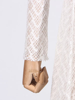 White lace maxi dress with mock neck and long sleeves, showing cuff detail.
