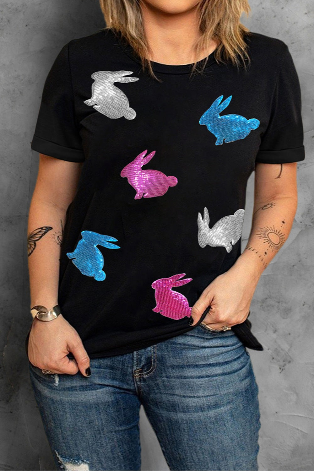 Black crewneck tee with scattered sequin bunny appliqués in pink, blue, and silver.