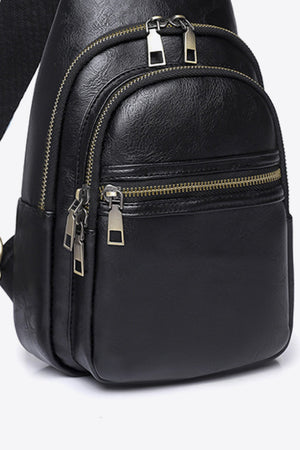 Black geometric strap sling bag with multiple zippered pockets and gold-tone hardware.