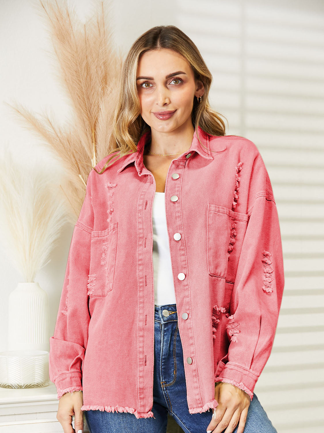 Distressed denim overshirt in orange-red with raw hem and button front.
