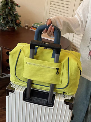 Chartreuse Oxford cloth duffle bag with front zip pocket and blue trim, held by a person.