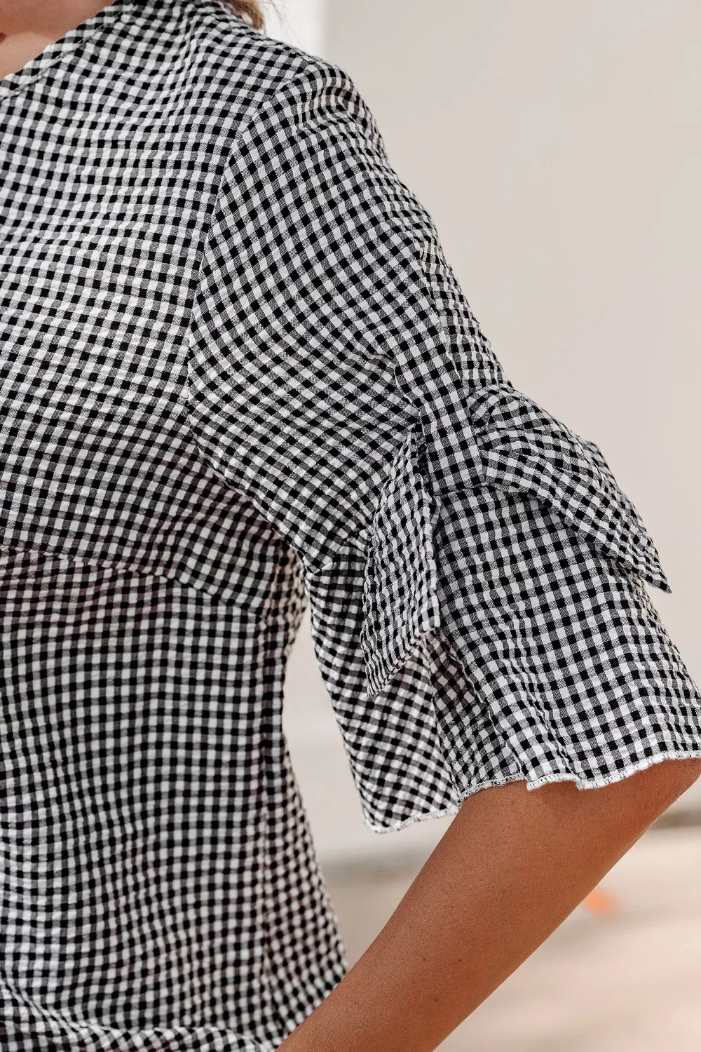 Gingham shirt with ruffled sleeve detail and polyester fabric.