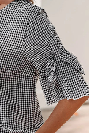 Gingham shirt with ruffled sleeve detail and polyester fabric.