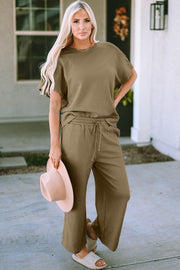 Khaki textured knit tee and wide leg pants set with drawstring waist, styled with a hat and slides.