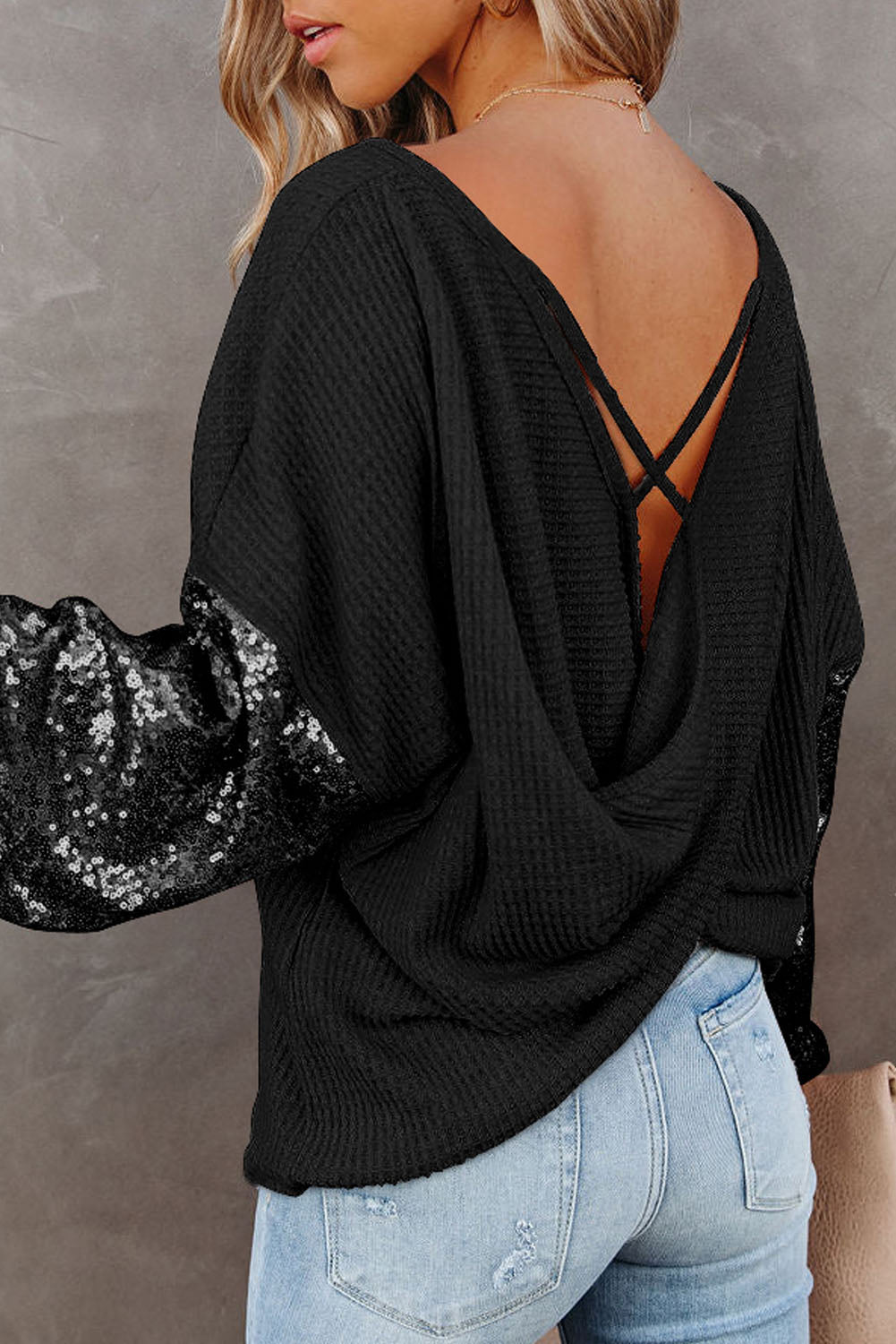 Black waffle knit top with sequin sleeves and criss-cross back detail