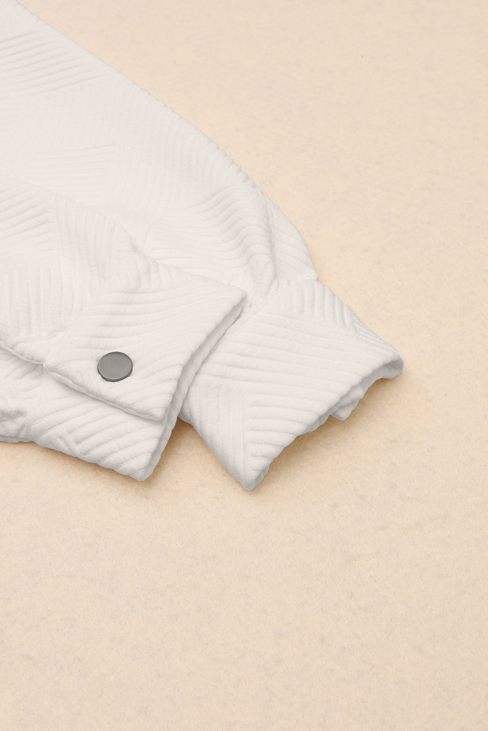 Textured ivory overshirt detail showing cuff and button closure.