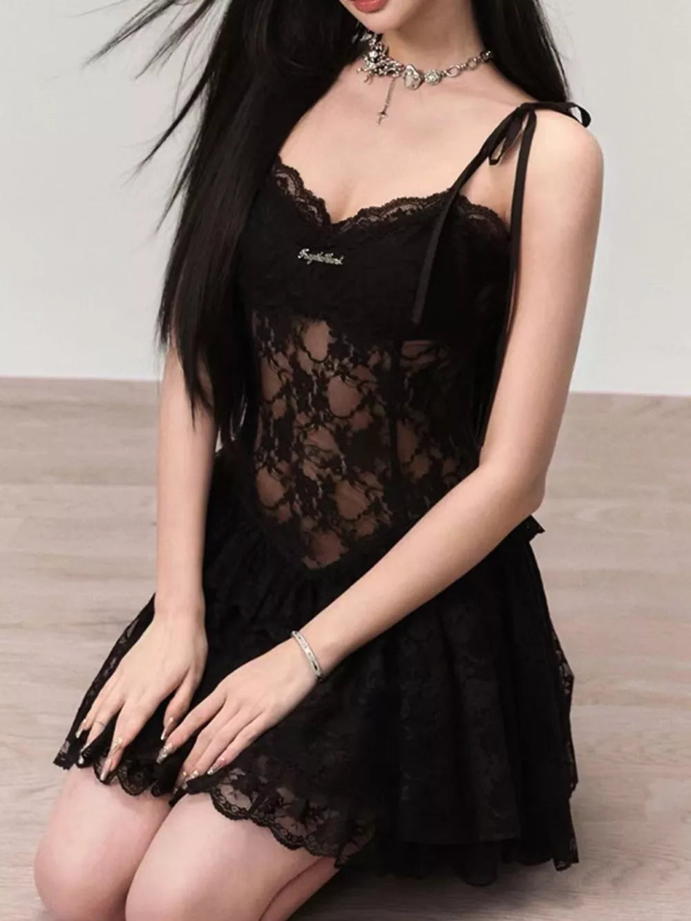 Black lace tie-shoulder mini dress with sheer bodice and ruffled skirt.