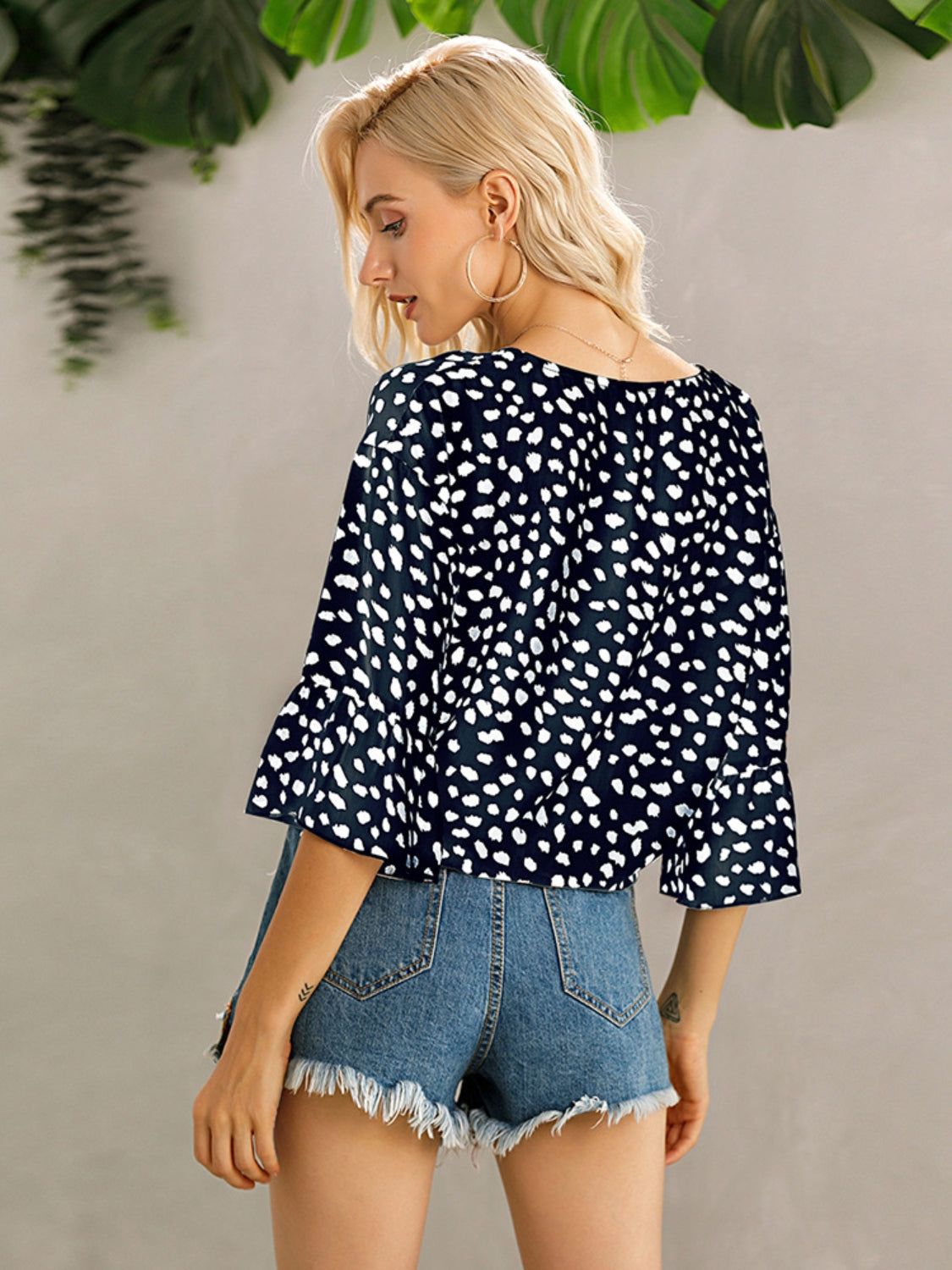 Dark blue spotted knot-front blouse with flared sleeves and a scoop neck.