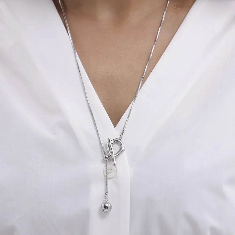 Silver lariat necklace with toggle closure and dangling ball charm.