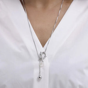 Silver lariat necklace with toggle closure and dangling ball charm.