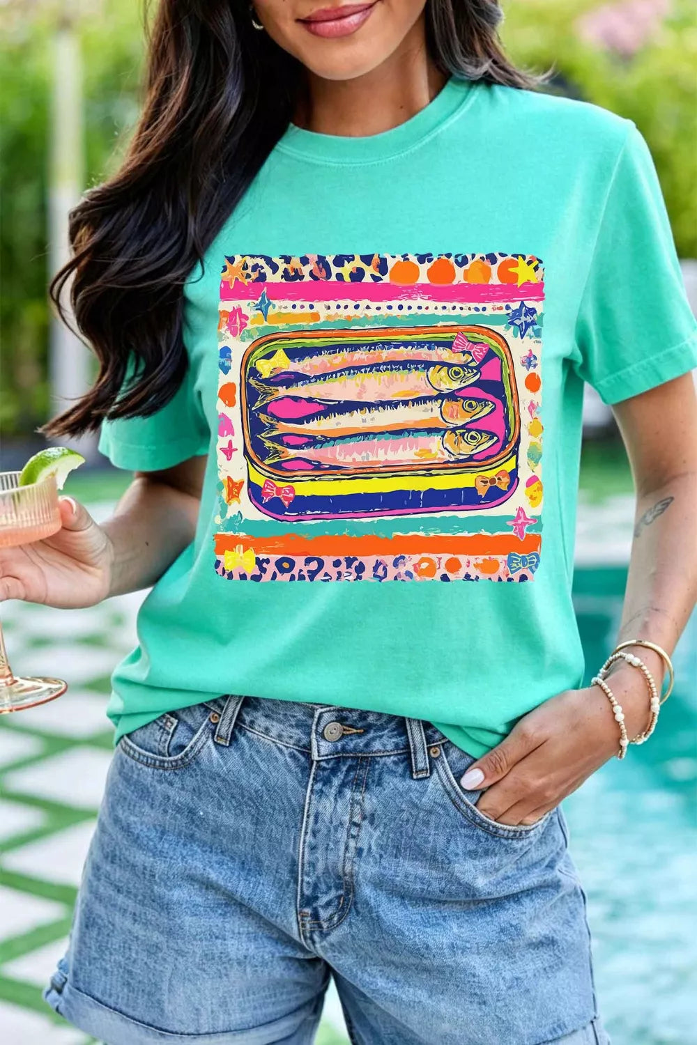Teal cotton crew neck t-shirt with a playful sardine can graphic and colorful abstract border.