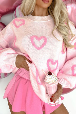 Pink knit sweater with heart appliques and balloon sleeves.
