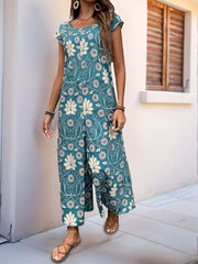 Botanical print culotte jumpsuit in dark green with short sleeves and a scoop neckline.