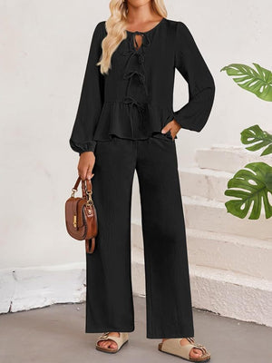 Black textured peplum tie-neck co-ord set with balloon sleeves and wide-leg pants.