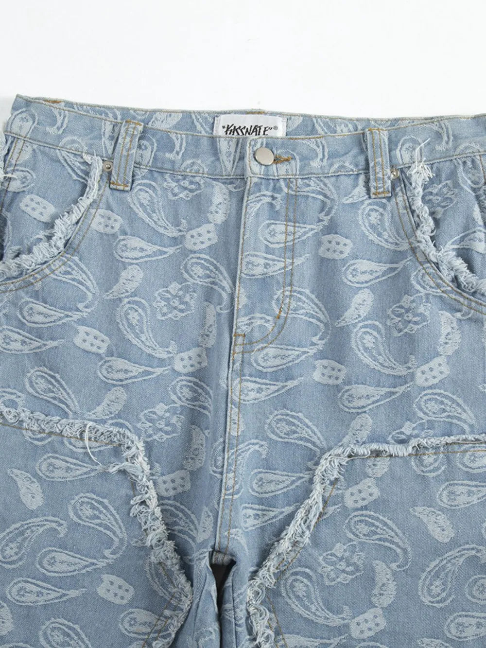 Light blue bootcut jeans with allover white paisley pattern and distressed frayed pockets.