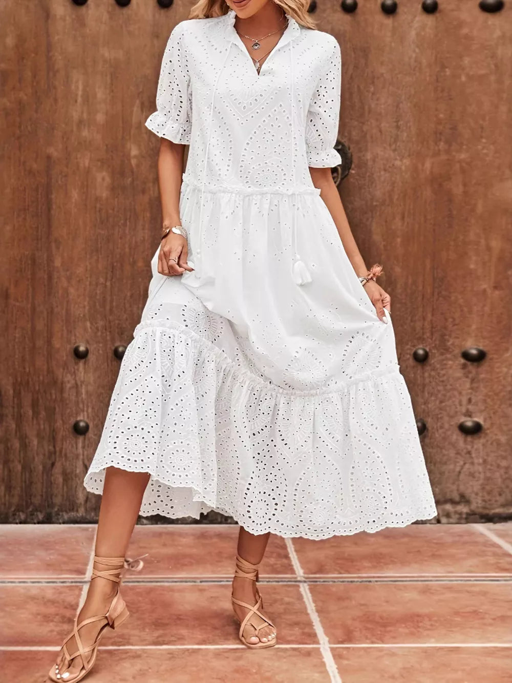 White embroidered eyelet midi dress with tie neck, short sleeves, and tiered skirt.
