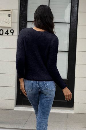 Black fluffy knit cardigan with crew neck and long sleeves, worn with denim jeans.