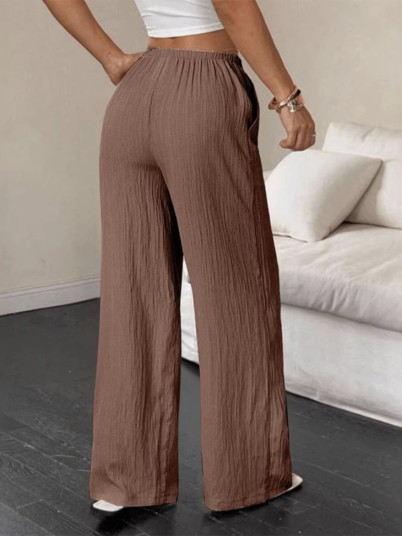 Brown crinkled wide-leg pants with drawstring waist and pockets.