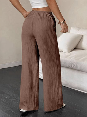 Brown crinkled wide-leg pants with drawstring waist and pockets.