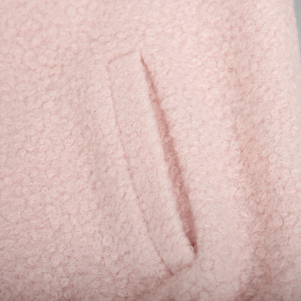 Blush pink textured bouclé bomber jacket with rounded neck and pocket detail.