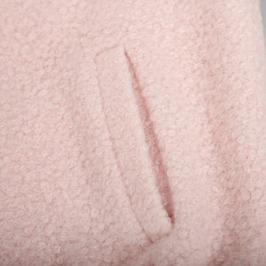 Blush pink textured bouclé bomber jacket with rounded neck and pocket detail.