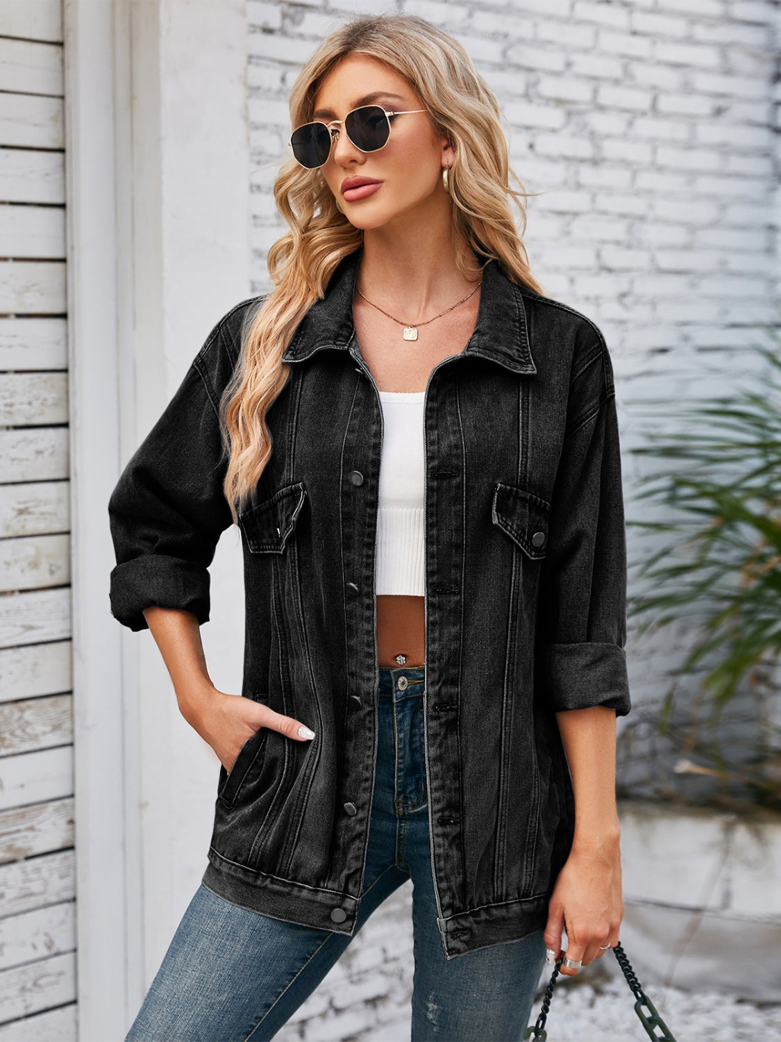 Black oversized denim trucker jacket with rolled sleeves and buttoned pockets.