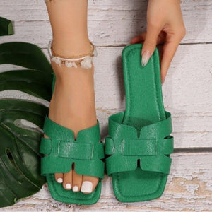 Green woven strap flat sandals with chic H-design straps.