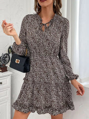 Ruffled tie neck floral mini dress in dark brown with long sleeves and tiered skirt.