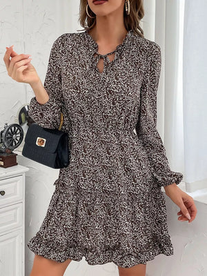 Ruffled tie neck floral mini dress in dark brown with long sleeves and tiered skirt.
