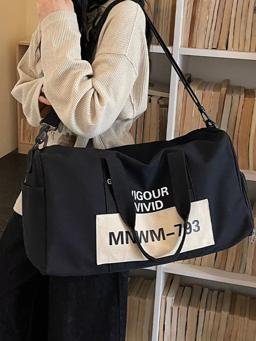 Black nylon travel bag with white graphic text detail and adjustable strap
