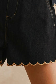 Black denim shorts with scalloped hem and contrast stitching.