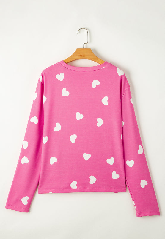 Hot pink long sleeve top with allover white hearts pattern, round neck.