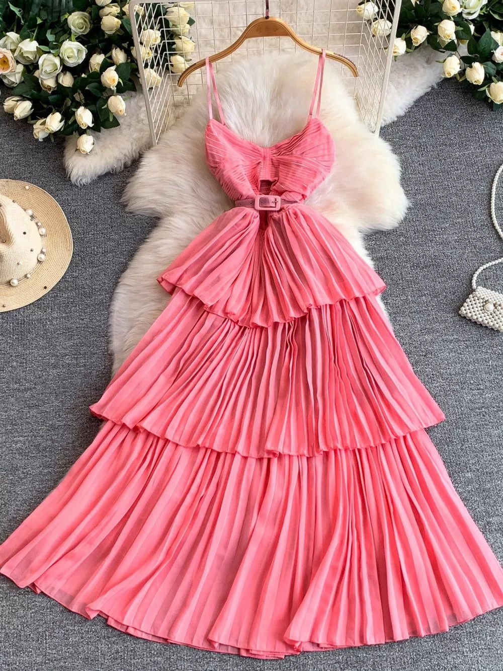 Pink belted pleated midi dress with spaghetti straps and tiered skirt