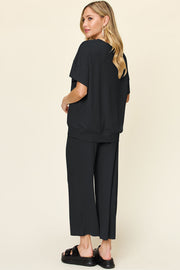 Black waffle knit lounge set with short sleeve top and wide leg pants.