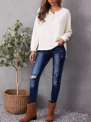 Ivory waffle knit henley shirt with button placket and side slits, styled with jeans.