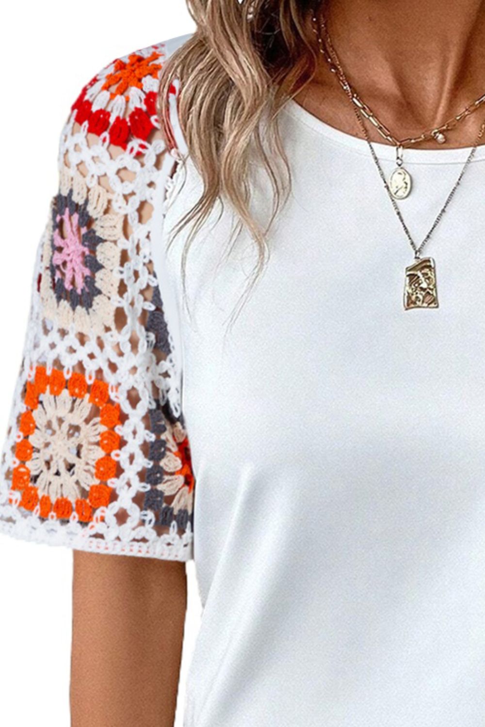 White t-shirt with colorful granny square crochet sleeves.