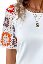 White t-shirt with colorful granny square crochet sleeves.