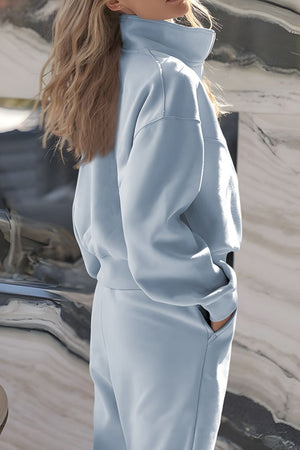 Light blue quarter-zip sweatshirt and jogger set with pockets.