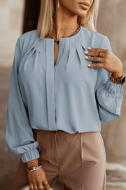 Misty Blue pleated yoke blouse with button detail and cinched cuffs.
