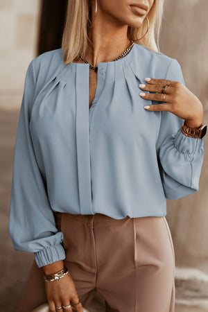 Misty Blue pleated yoke blouse with button detail and cinched cuffs.
