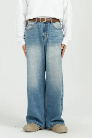 Wide-leg denim jeans in medium wash with pockets and a brown belt.