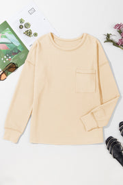 Tan ribbed knit long sleeve top with a patch pocket and crew neck.