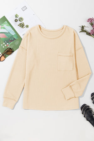 Tan ribbed knit long sleeve top with a patch pocket and crew neck.
