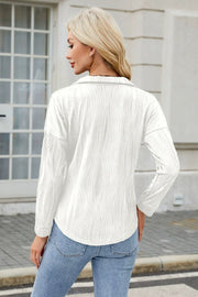White collared blouse with wave-effect texture and long sleeves.