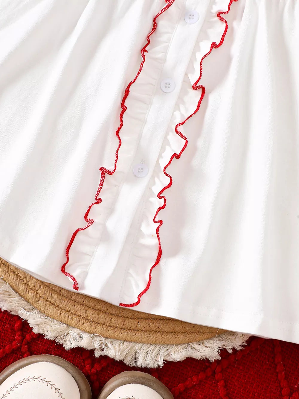 White cotton baby dress with red embroidered ruffles and buttons.