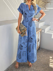 Blue geometric print wide-leg jumpsuit with V-neck and short sleeves.