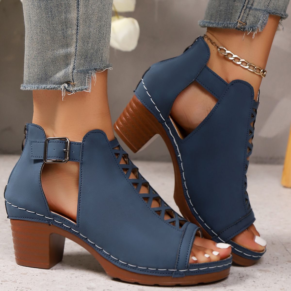 Navy blue criss-cross cut-out block heel sandals with ankle strap and buckle detail.
