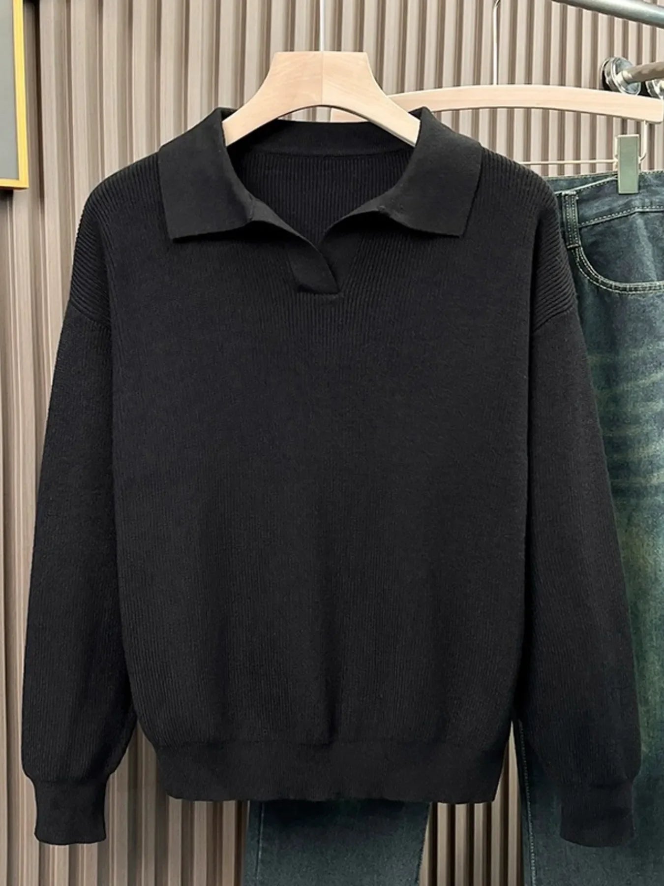 Black collared knit sweater with ribbed texture and a relaxed fit.