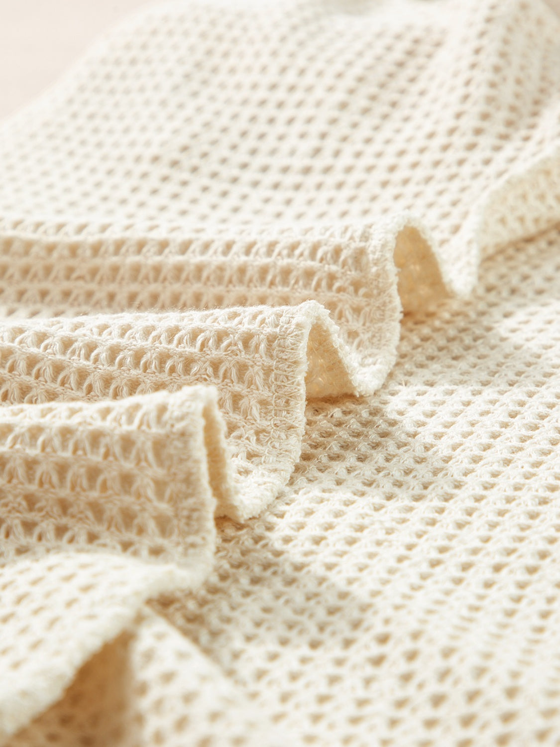 Cream waffle knit fabric with textured weave and soft drape