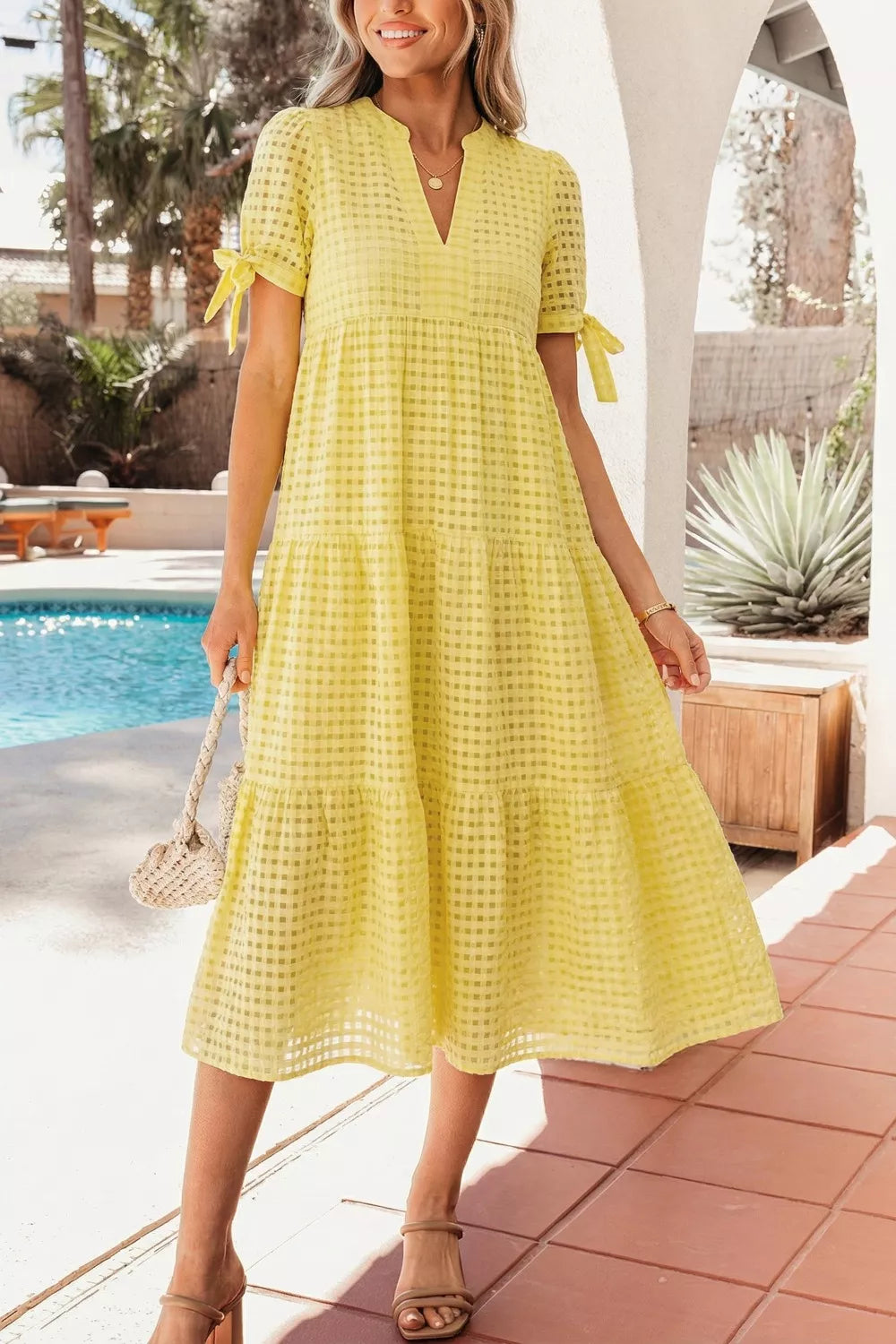 Yellow gingham midi dress with V-neck, short sleeves with bow ties, and tiered skirt.